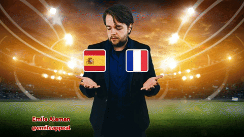 A Man Standing In Front Of A Stadium With A Spanish And French Flag GIF
