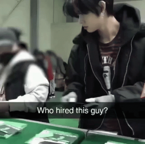 A Man Standing In Front Of A Table With The Words Who Hired This Guy On The Bottom GIF
