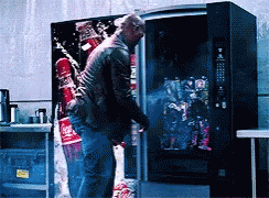 A Man Standing In Front Of A Vending Machine With A Coca Cola Advertisement On It GIF