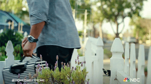 A Man Standing In Front Of A White Picket Fence With The Hashtag #Homesweethome On The Bottom GIF
