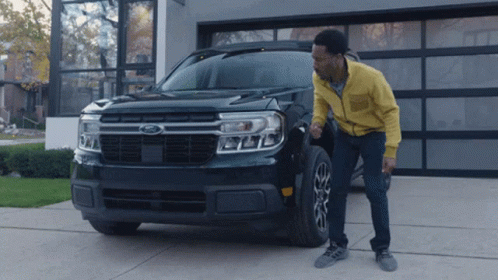 A Man Standing Next To A Black Ford Truck GIF