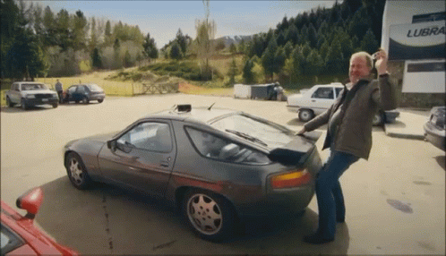 A Man Standing Next To A Car In Front Of A Building That Says Lube GIF