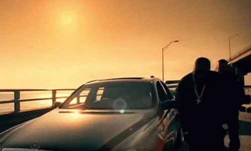 A Man Standing Next To A Car With The Sun Shining Through The Windshield GIF