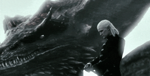 A Man Standing Next To A Large Dragon With A Sword In His Hand GIF
