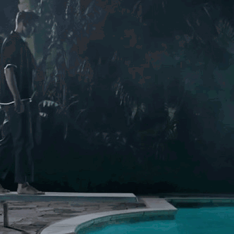 A Man Standing Next To A Pool At Night GIF