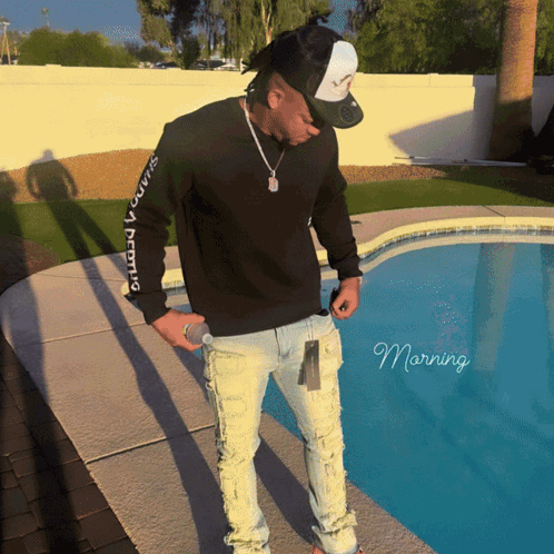 A Man Standing Next To A Pool Wearing A Black Sweatshirt That Says ' Squad ' On It GIF