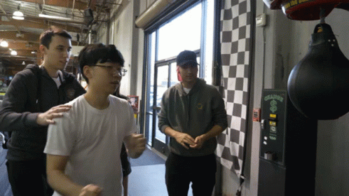 A Man Standing Next To A Punching Bag That Says ' Ching ' On It GIF