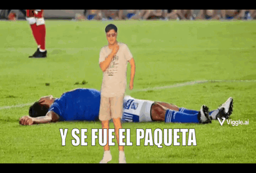 A Man Standing Next To A Soccer Player Laying On The Field With The Words Y Se Fue El Paqueta Below GIF