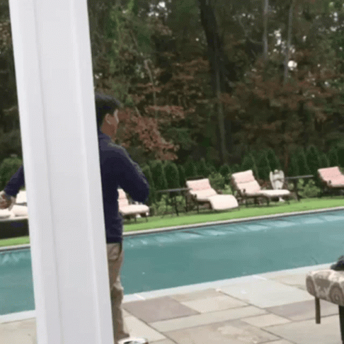 A Man Standing Next To A Swimming Pool Talking On His Phone GIF