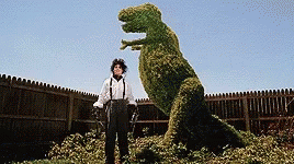 A Man Standing Next To A T-Rex Made Of Plants GIF