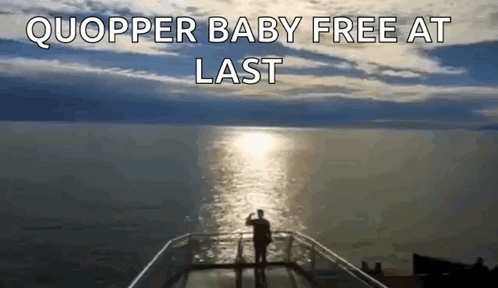 A Man Standing On A Balcony Overlooking A Body Of Water With The Words Quopper Baby Free At Last Above Him GIF