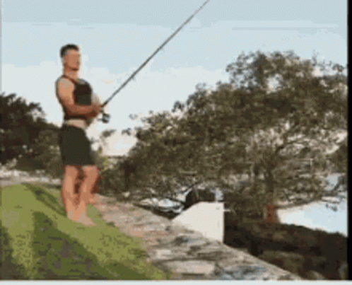 A Man Standing On A Ledge Holding A Fishing Pole GIF