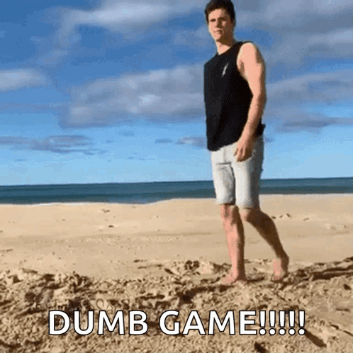A Man Standing On A Sandy Beach With The Words Dumb Game !!! GIF