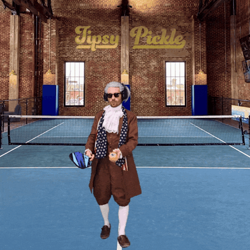 A Man Standing On A Tennis Court With A Sign That Says Tipsy Pickle Behind Him GIF