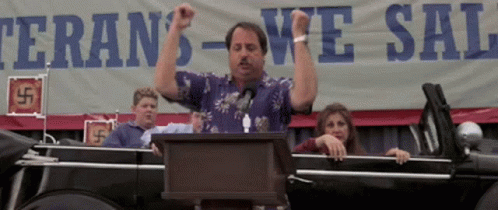 A Man Stands At A Podium In Front Of A Sign That Says Veteran 'S We Sal GIF