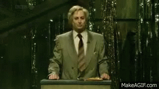 A Man Stands At A Podium With A Sign That Says " Remain Indoors " GIF