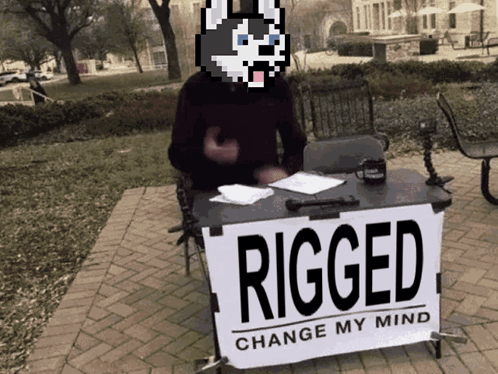 A Man Stands Behind A Sign That Says Rigged Change My Mind GIF