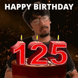 A Man Stands In Front Of A Birthday Cake With Candles That Say 125 GIF