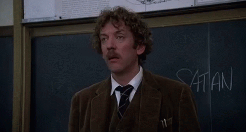 a man stands in front of a blackboard with the words listen i 'm not joking written on it
