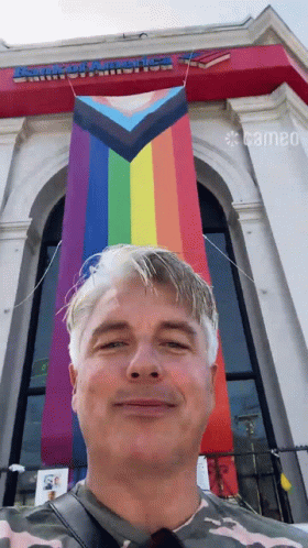 A Man Stands In Front Of A Building That Says Armored America On It GIF