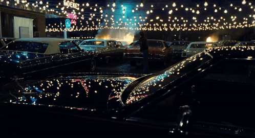 A Man Stands In Front Of A Burning Car In A Parking Lot With A Sign That Says Stop GIF