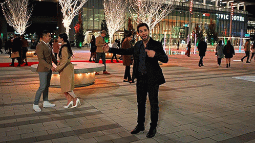 A Man Stands In Front Of A Civic Hotel At Night GIF