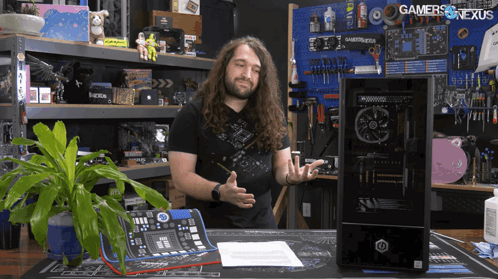 A Man Stands In Front Of A Computer With The Words Gamers Nexus Written On The Wall Behind Him GIF