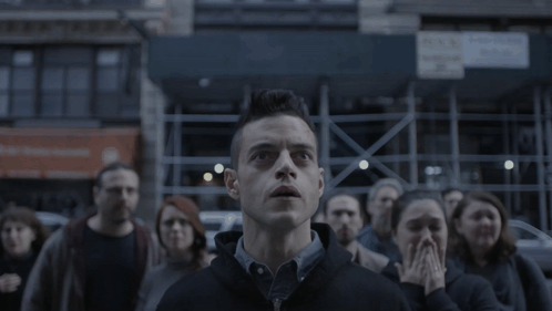 A Man Stands In Front Of A Crowd Looking Up GIF