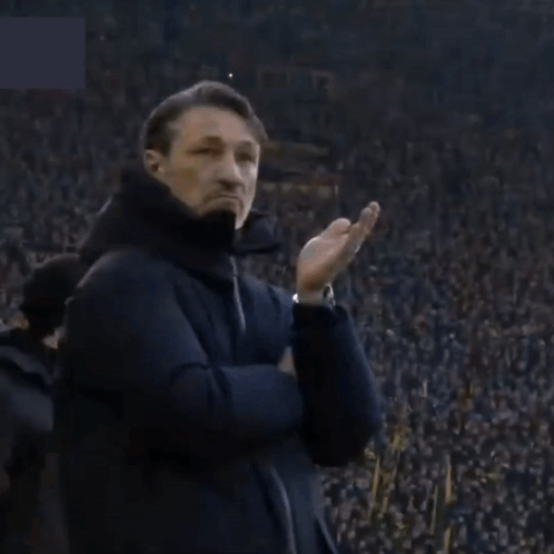 a man stands in front of a crowd with a sign that says ' allianz '