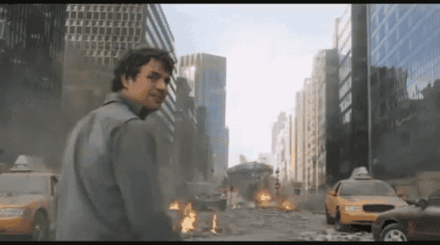 A Man Stands In Front Of A Destroyed City With A Taxi Cab In The Foreground GIF