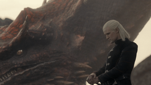 A Man Stands In Front Of A Dragon With A Sword GIF