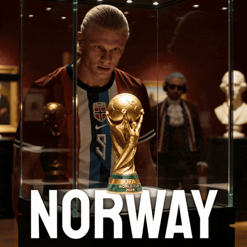 a man stands in front of a fifa world cup trophy in a glass case