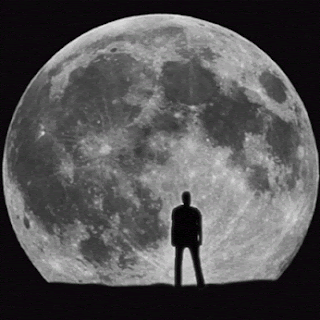 A Man Stands In Front Of A Full Moon In A Black And White Photo GIF