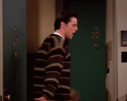A Man Stands In Front Of A Green Door With The Number 20 Written On It GIF