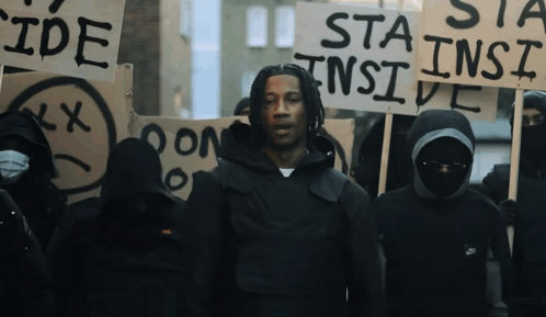 A Man Stands In Front Of A Group Of People Holding Signs Including One That Says " Sta Ins Ide " GIF