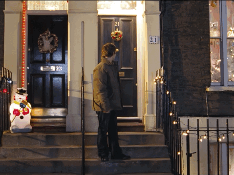 A Man Stands In Front Of A House With The Number 21 On The Front Door GIF