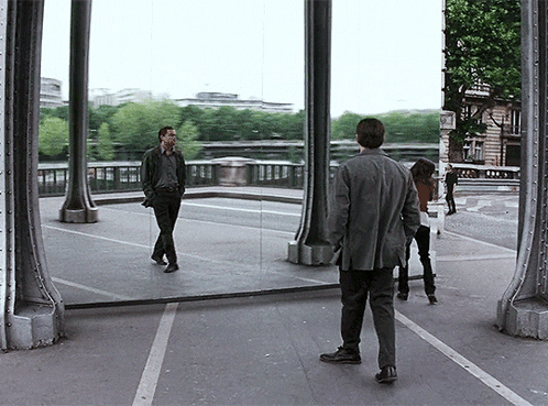 A Man Stands In Front Of A Large Mirror Looking At His Reflection In The Mirror GIF