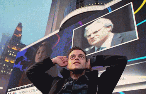 A Man Stands In Front Of A Large Screen That Says Breaking News GIF