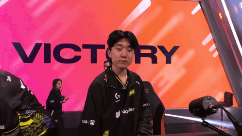 A Man Stands In Front Of A Large Victory Sign GIF