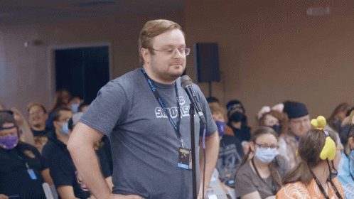 a man stands in front of a microphone wearing a shirt that says sdue