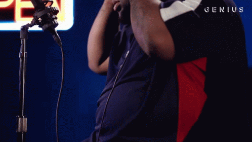 A Man Stands In Front Of A Microphone With Genius Written On The Bottom Right GIF