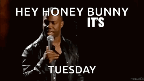 A Man Stands In Front Of A Microphone With The Words Hey Honey Bunny It 'S About To Go Down Tuesday Below Him GIF