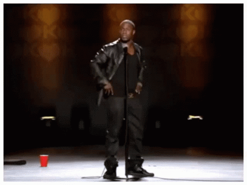 A Man Stands In Front Of A Microphone With The Words " Look Look Look " Behind Him GIF