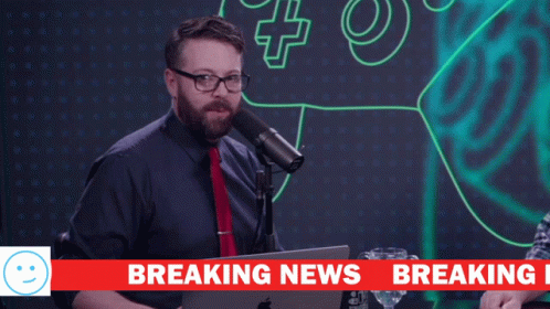 a man stands in front of a microphone with the words we have breaking above him