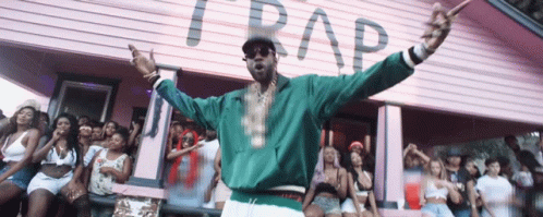A Man Stands In Front Of A Pink Building That Says Trap On It GIF