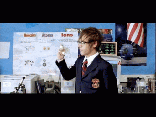 A Man Stands In Front Of A Poster About Molecules And Atoms GIF