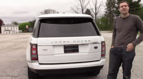 A Man Stands In Front Of A Range Rover GIF