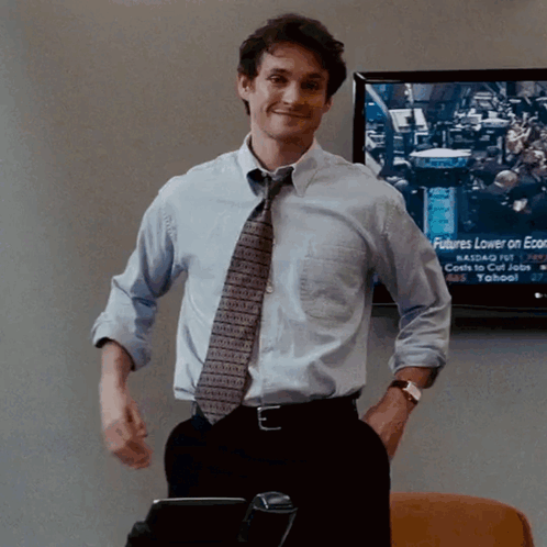 A Man Stands In Front Of A Screen That Says Futures Lower On Economic News GIF