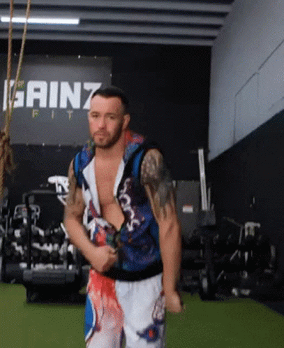 A Man Stands In Front Of A Sign That Says Gainz GIF
