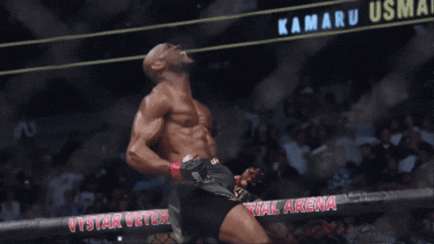 A Man Stands In Front Of A Sign That Says Kamaru Usma On It GIF